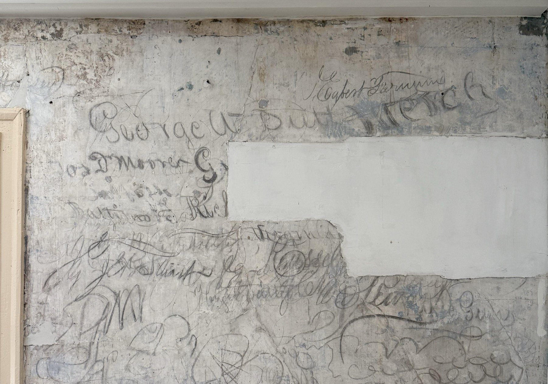 A whitewashed plaster wall at the Graffiti House covered in pencil signatures and drawings left by Civil War soldiers, including the name George W. Bell.